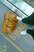 person stranding beside brown leather handbag