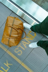 person stranding beside brown leather handbag