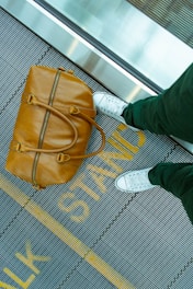 person stranding beside brown leather handbag