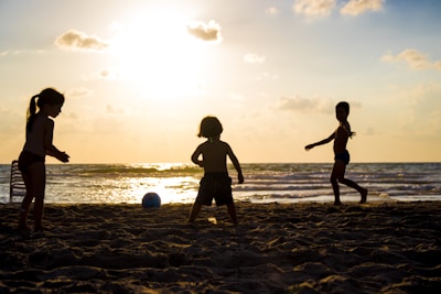 silhouette of three children on beach