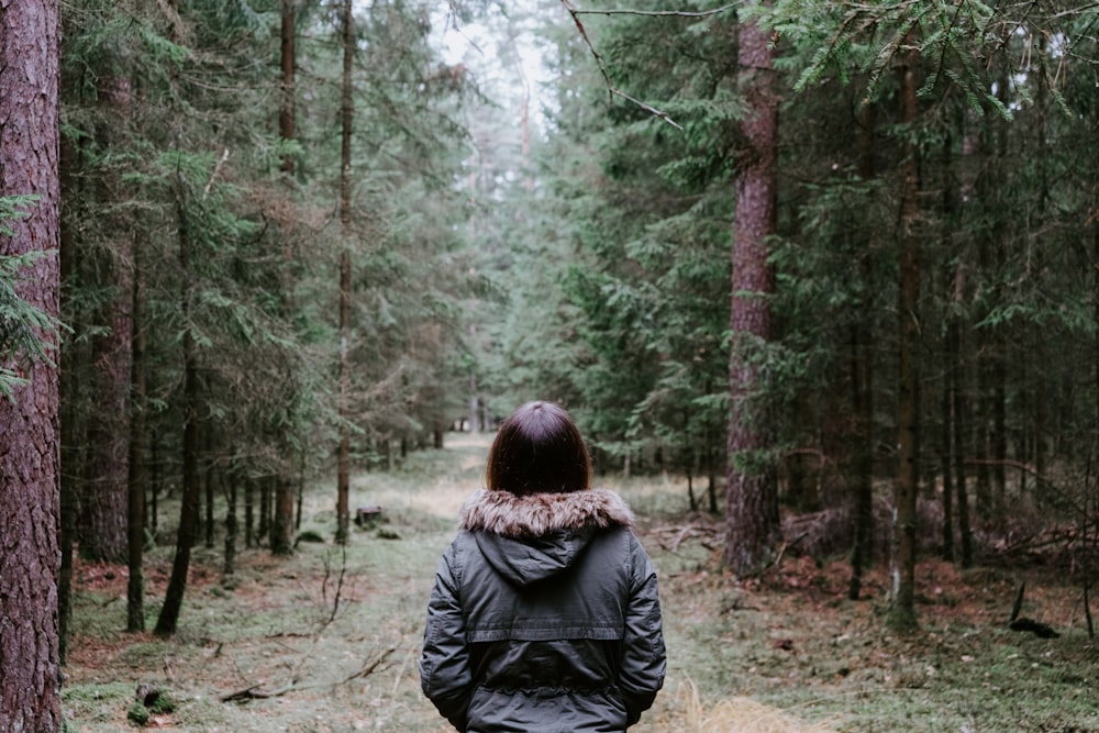 person wearing jacket standing on forest