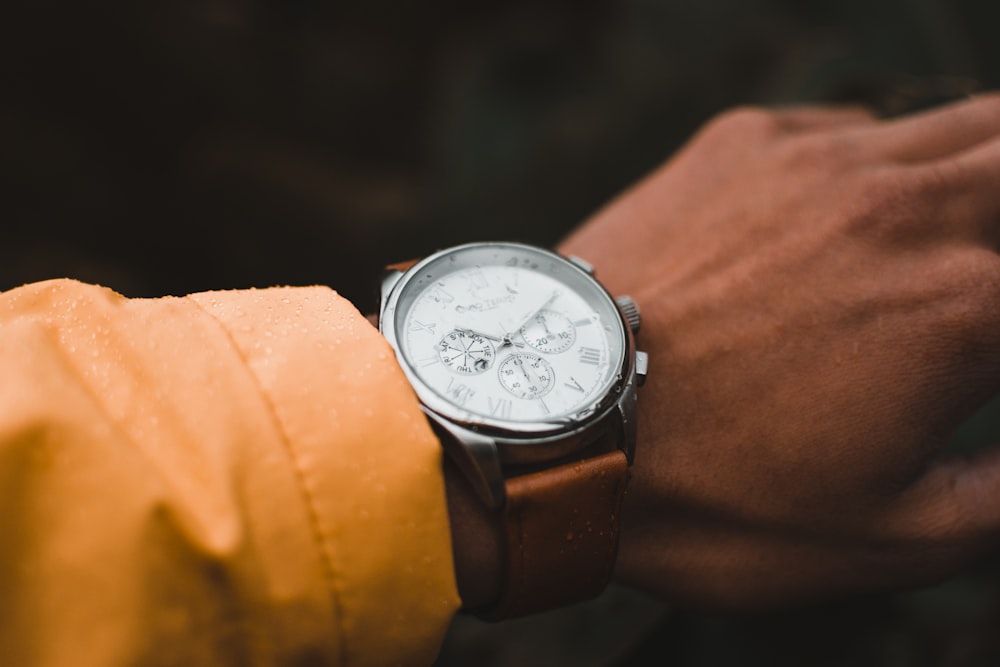 person wearing round silver-colored chronograph watch