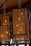 Hanging rectangular lanterns with intricate perforated designs give off a warm glow. The wooden frame and detailed patterns create a cozy and artistic atmosphere. The ceiling appears to be made of wood, adding to the rustic ambiance.