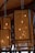 Hanging rectangular lanterns with intricate perforated designs give off a warm glow. The wooden frame and detailed patterns create a cozy and artistic atmosphere. The ceiling appears to be made of wood, adding to the rustic ambiance.