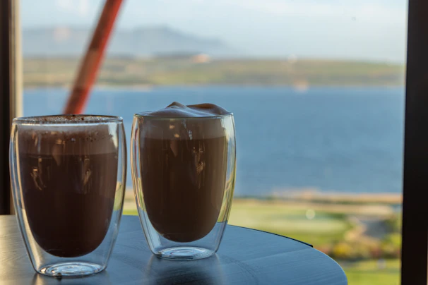 Freshly brewed coffee served in a handmade cup, set on a wooden table beside a window overlooking the garden.