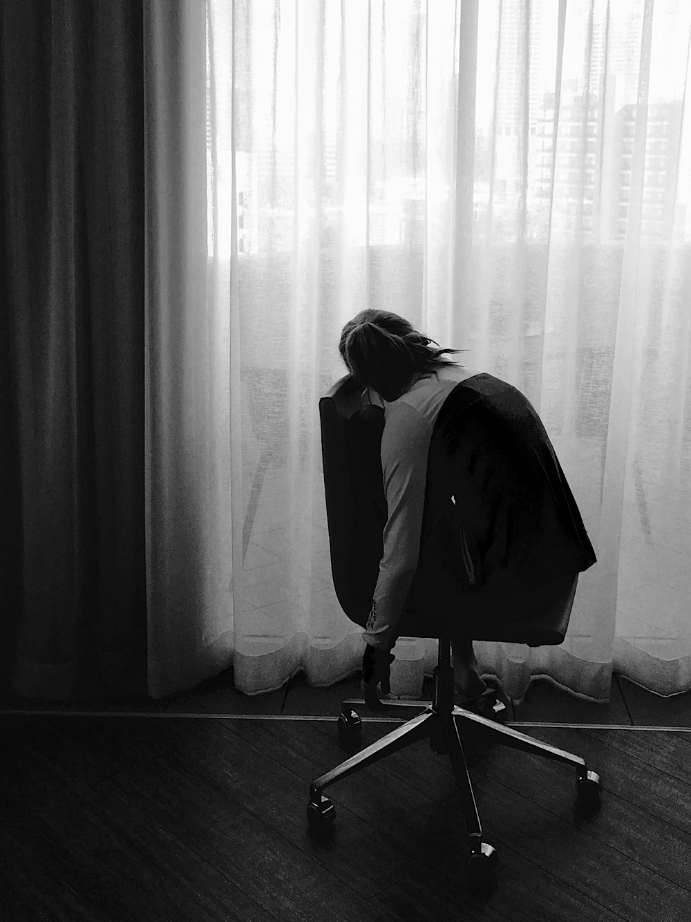 grayscale photo of woman sitting on rolling chair