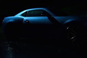 Close-up of a microcar's glossy exterior reflecting soft lighting in dark blue tones