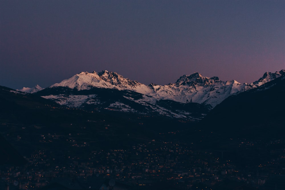 a view of a snowy mountain range at night
