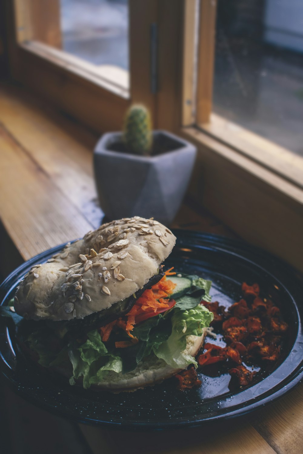 burger on black plate beside purple ceramic vase