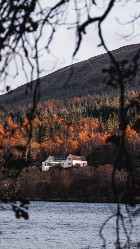 white house in forest near lake in Loch Venachar United Kingdom