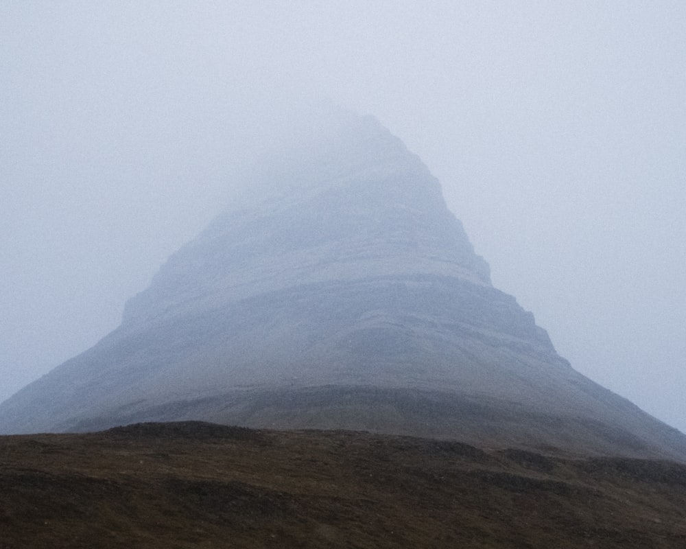 a very tall mountain in the fog on a cloudy day