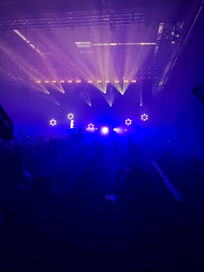 Close-up of a sleek stage spotlight casting vibrant blue hues over a live music performance.