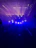 A close-up of a sleek moving head stage light casting electric blue beams across a dark venue.