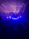 A close-up of a sleek moving head stage light casting electric blue beams across a dark venue.