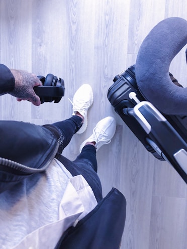 A traveler wearing noise-canceling headphones and holding a travel pillow.