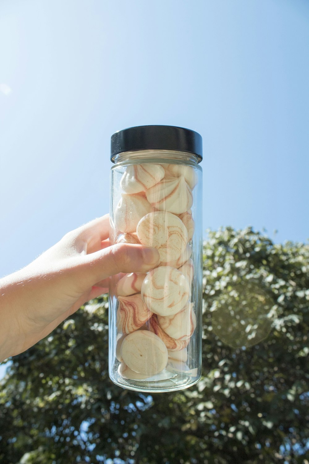 person holding clear glass container