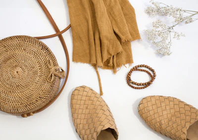 A flat lay of dresply accessories including a neutral-toned scarf, sunglasses, and a minimalist handbag on a clean surface