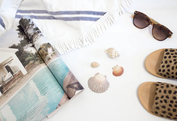 Sunglasses, slides, a towel and shells laid out