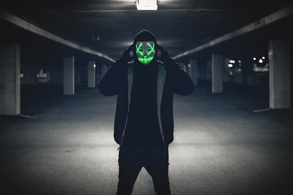 man wearing black jacket and red LED mask