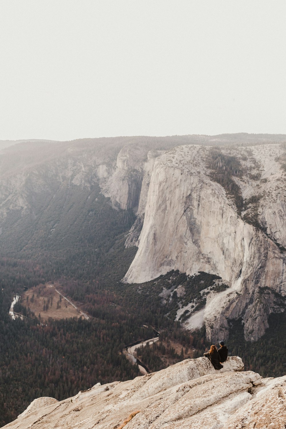 two person sitting on rocky hill viewing mountain