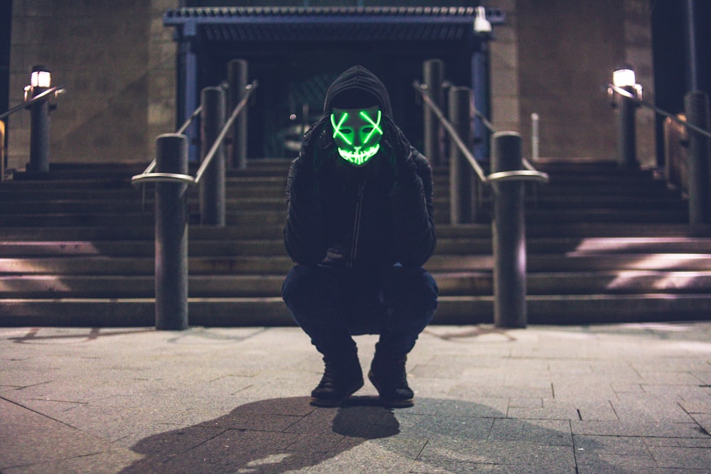 man wearing pullover hoodie and green LED mask