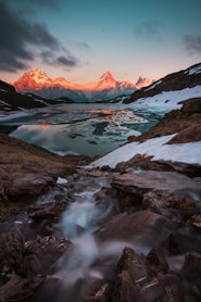 body of water surrounded with snowcapped mountains at daytime