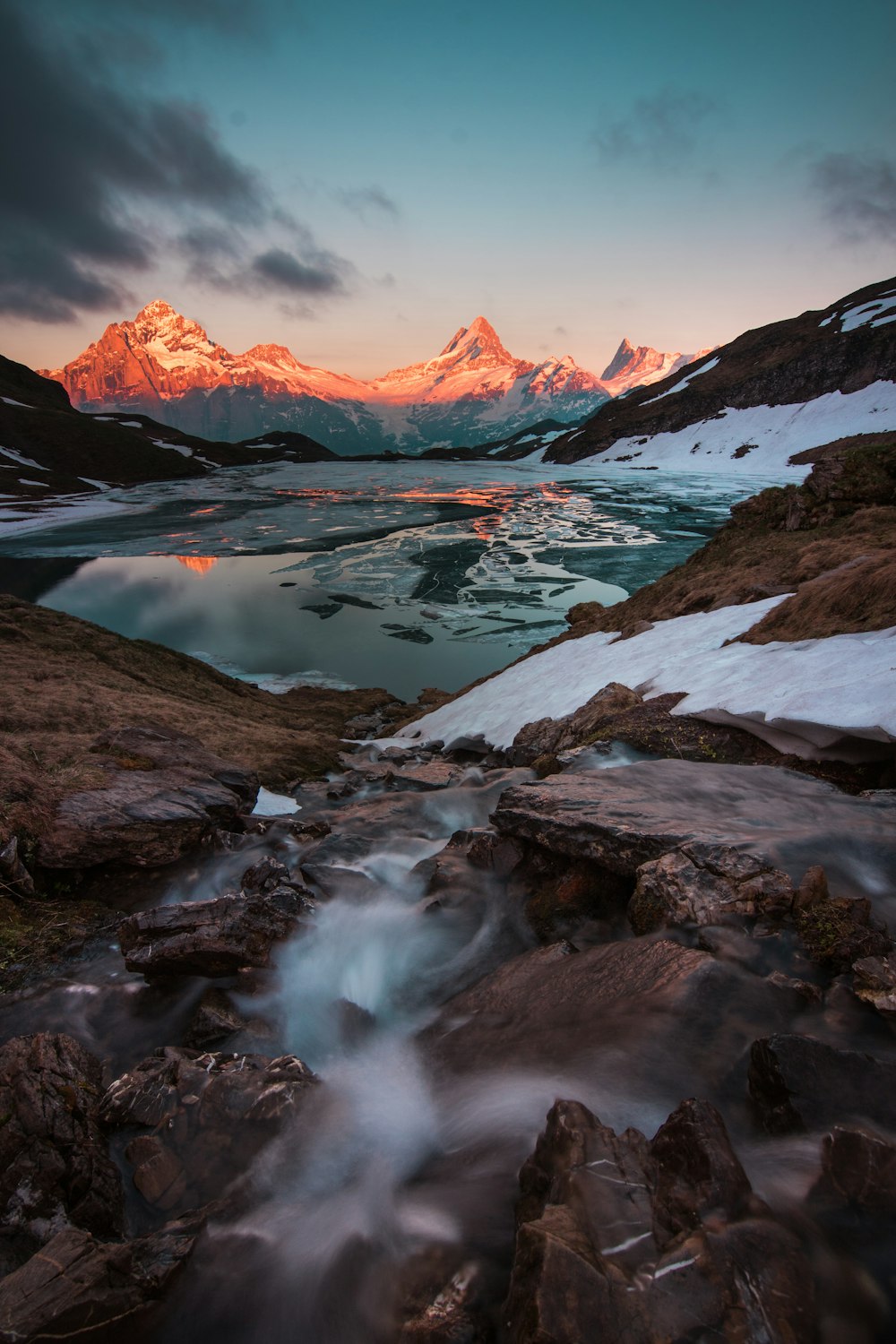 body of water surrounded with snowcapped mountains at daytime