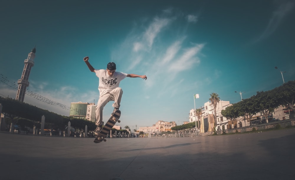 man skating on concrete road under blue and white skies