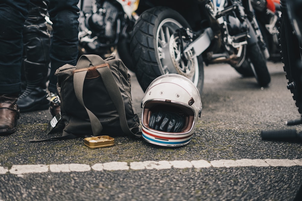 道路上の黒いバックパックの横にある白いヘルメット