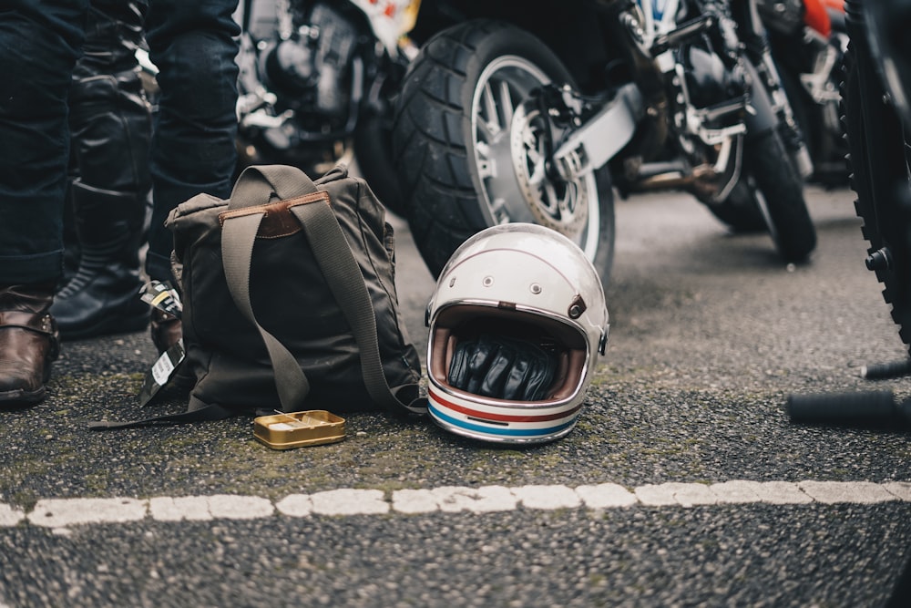 Casque blanc à côté d’un sac à dos noir sur la route