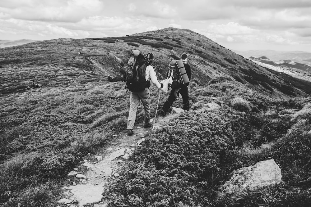 two people walking on mountain in grayscale photography