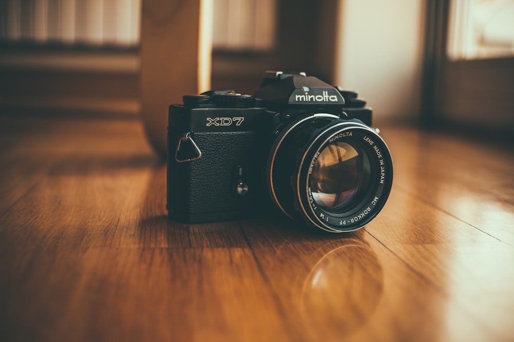 câmera Minolta SLR preta no piso de madeira marrom