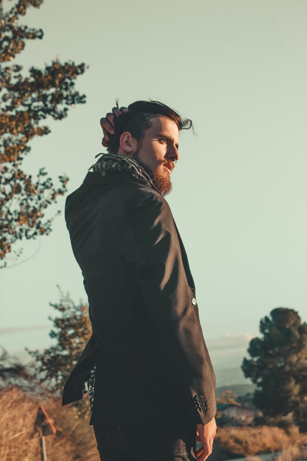 man wearing black dress jacket near tree during daytime