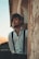 man wearing white button-up dress shirt and suspenders leaning on brown and white concrete wall