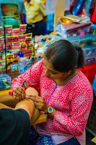 woman doing tattoo on person's arm