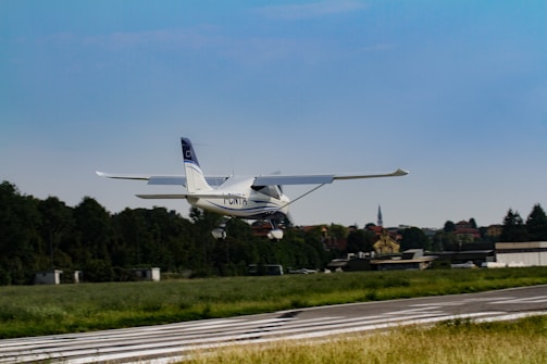 A small plane taking off into a clear blue sky over a green landscape.