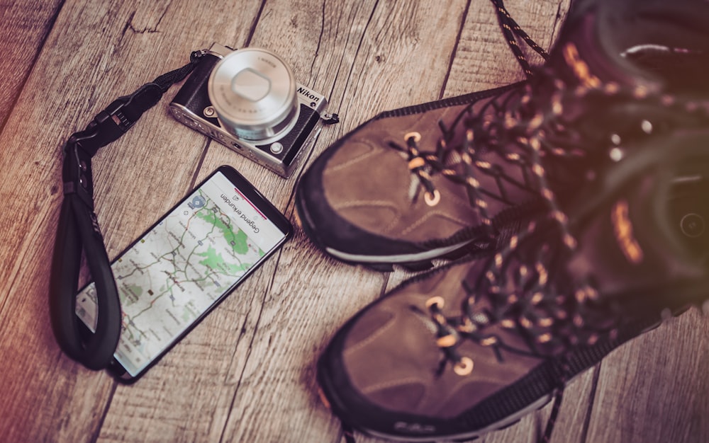 black smartphone beside camera and boots