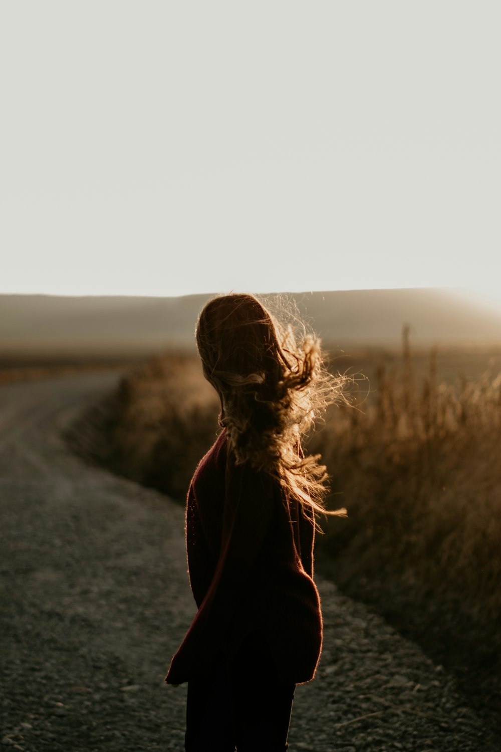 woman standing on dirt road during daytime