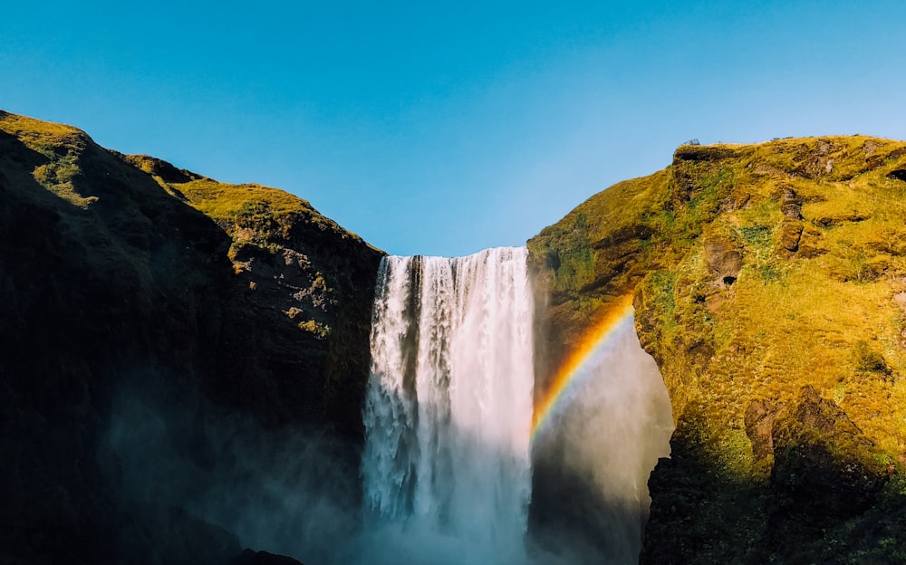 waterfalls with rainbow under clear sky at daytime