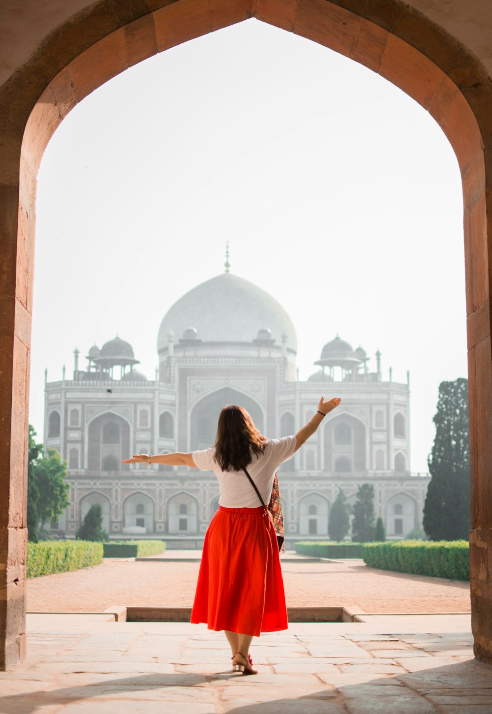 woman with hands on air facing mosque