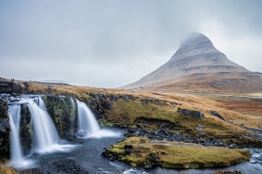 waterfalls near mountains during daytime in Kirkjufell Mountain Iceland