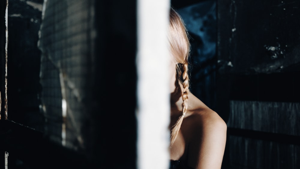 a woman with long hair standing in front of a window