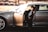 Chauffeur opening the door of a luxury vehicle for a stylish passenger.