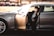 Chauffeur opening the door of a luxury vehicle for a stylish passenger.