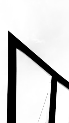A black geometric structure with sharp angles is set against a stark white background, creating a minimalist and modern aesthetic.