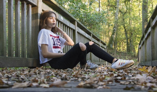 Model walking outdoors wearing a relaxed fit t-shirt and jeans, surrounded by autumn leaves
