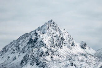 A rugged mountain peak silhouetted against a stormy sky, symbolizing strength and perseverance.