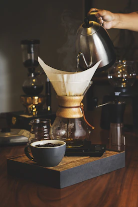 person pouring water in clear glass jar