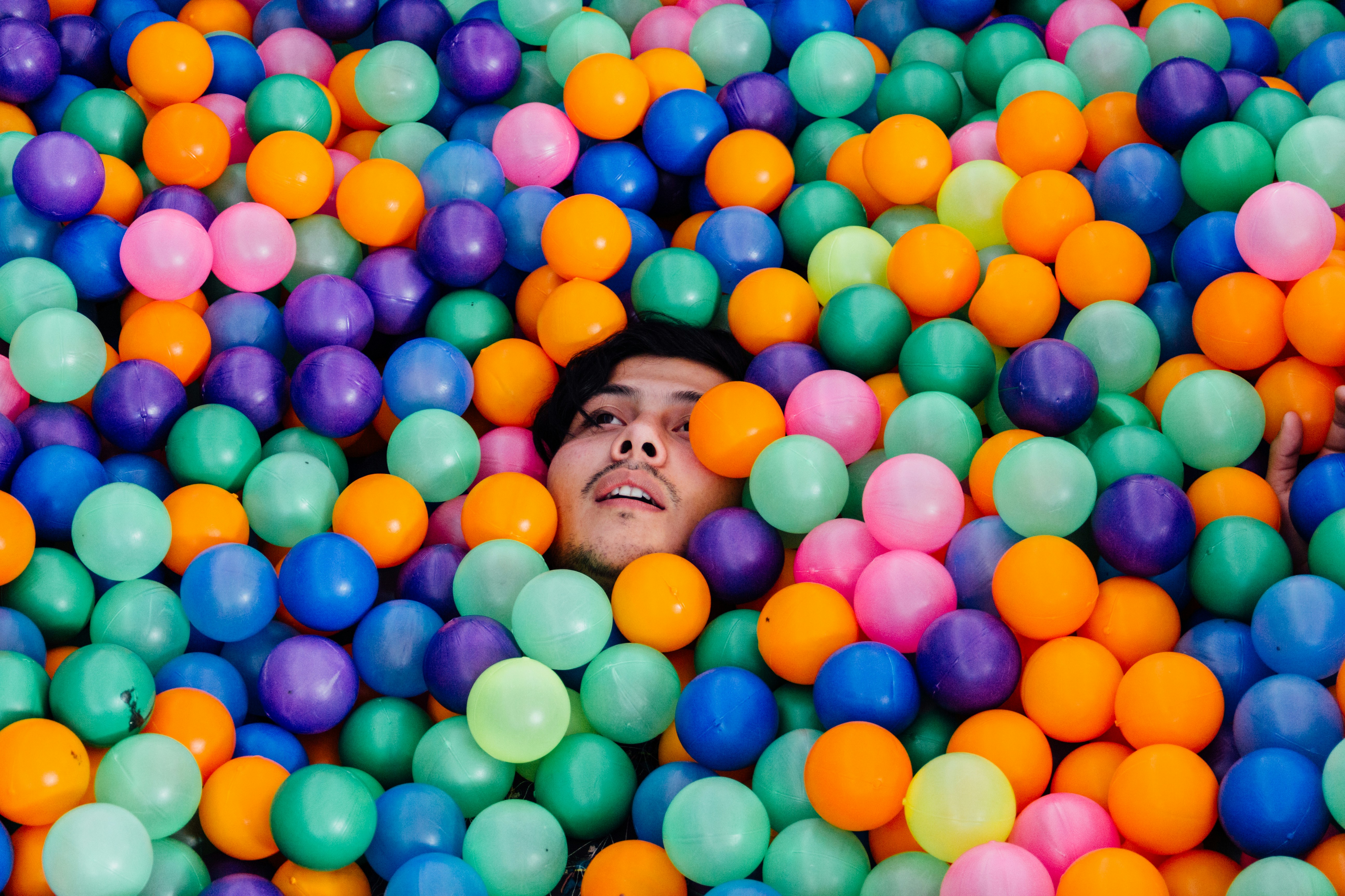 man lying in ball pit conceptual teams background