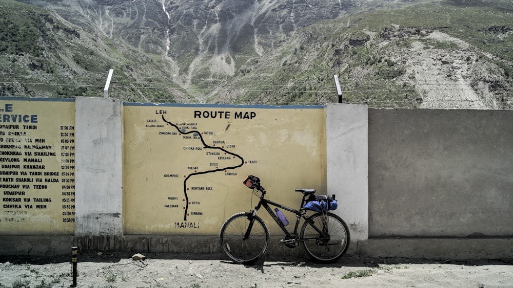 Mountain bike preta estacionada ao lado de parede de concreto